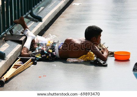 BANGKOK - JANUARY 10: Thai crippled man begs for money on a bridge on January 10, 2010 in Bangkok, Thailand.