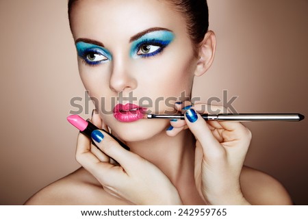 Makeup artist applies lipstick. Beautiful woman face. Perfect makeup