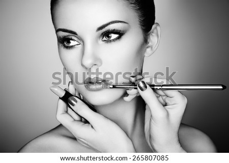 Makeup artist applies lipstick. Beautiful woman face. Perfect makeup. Black and white
