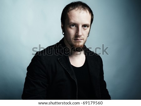 Artistic dark portrait of the young beautiful man with dark eyes. Shooting in studio