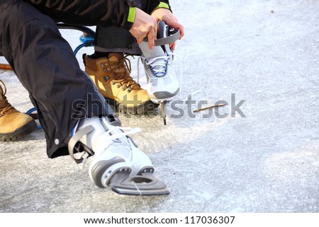 Tying laces of ice hockey skates at skating rink