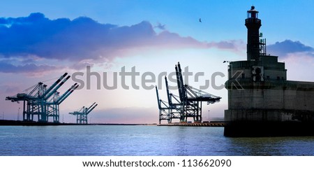 Cargo sea port. Old lighthouse. Sea cargo cranes. Sunrise. Panorama.