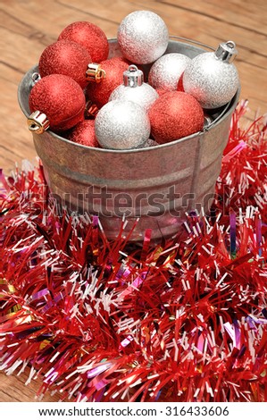 A bucket filled with silver and red baubles to decorate a Christmas tree