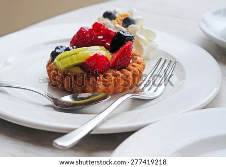 delicious artisanal shortbread fruit cake and whipped cream on white plate with silver fork and spoon, selective focus
