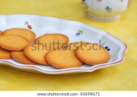 Butter biscuits or cookies on plate on yellow table-cloth, shallow dof