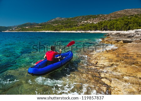 Man rowing in inflatable kayak at Adriatic sea. Hvar island coast, popular touristic destination of Croatia.