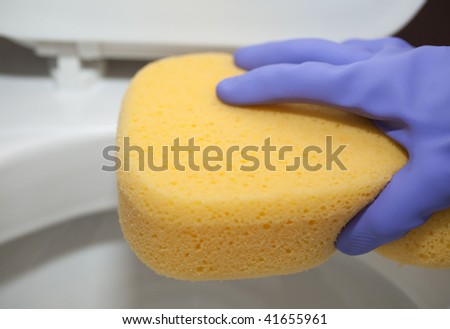 cleaning a toilet with a big sponge, wearing rubber gloves