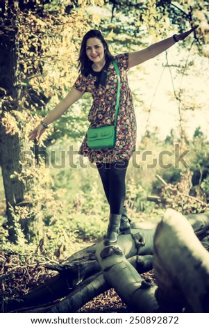 playful woman balancing on a branch, vintage filter effect added
