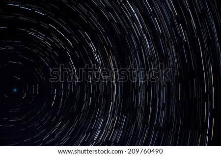 Traces of stars revolving around the pole star on black sky, shot long exposure. Can be used as background.
