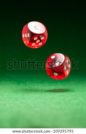 Rolling red dice over green surface
