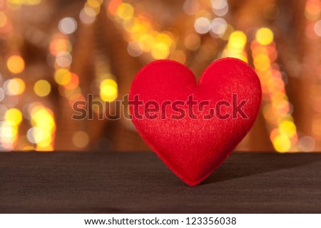 Red heart in front of a red gold sparkling background