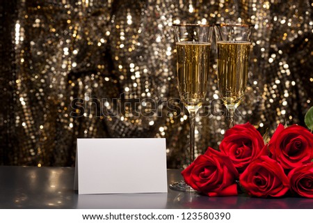 Champagne glasses and roses in front of gold glitter background
