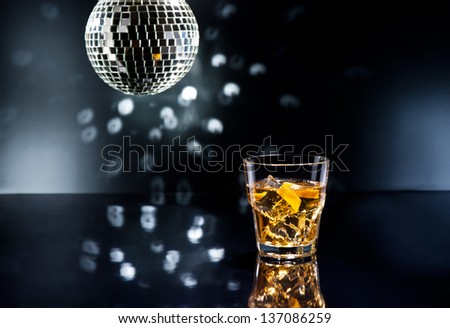 Whiskey sour cocktail in a disco setting with orange peel