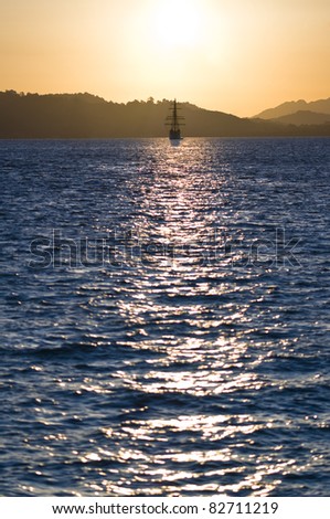 sailboat bathed in dawn sunlight whereby the sun produces nice reflection in the ocean
