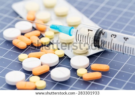 Heap of medicine pills and injection syringe