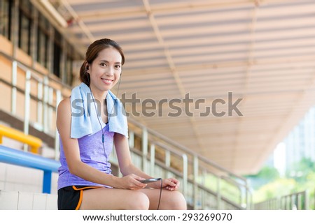 Woman using the cellphone and listen to music after running