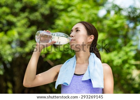 Young woman having rest after sport exercises holding bottle of water