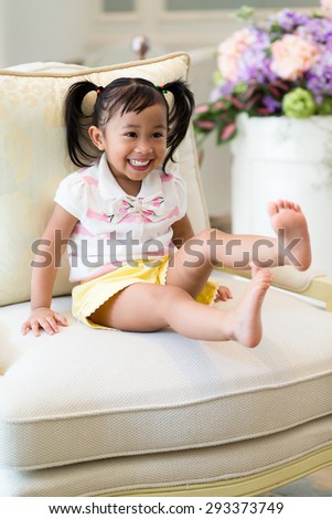 Thrilled little girl sitting on couch