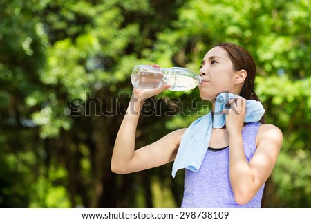 Beautiful young asian woman drinking water after training