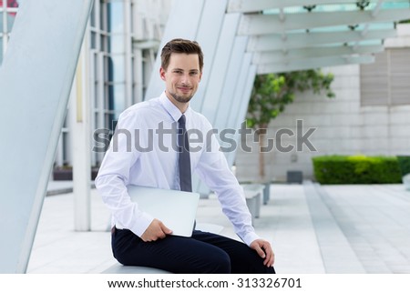 Caucasian businessman with laptop computer and sitting outside