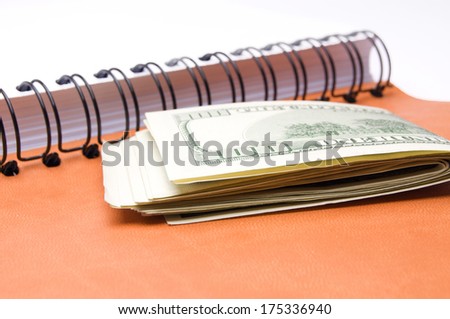 Hundred dollar bills money and a stack of notebooks