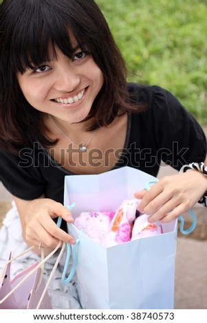 Beautiful young Japanese girl excited over her shopping bags