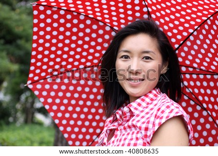 Beautiful young Chinese girl with red umbrella and shirt standing proud