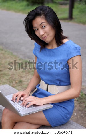 Attractive Chinese woman working with laptop outdoors