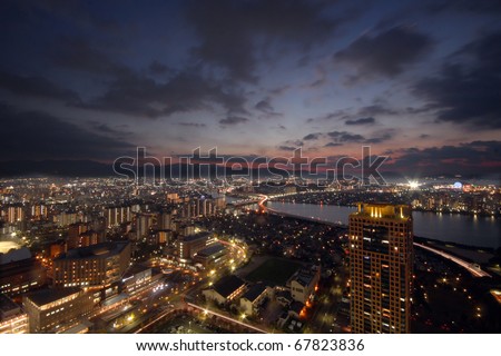 Sun setting over city with light up buildings in Japan