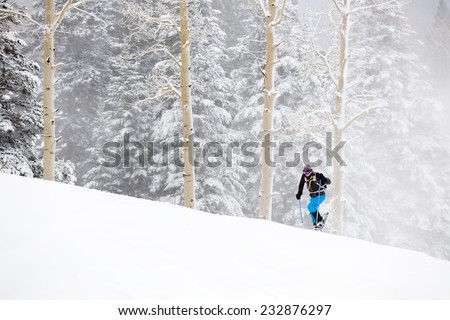 Young Man Snowshoeing Up Hill in Wintry Storm
