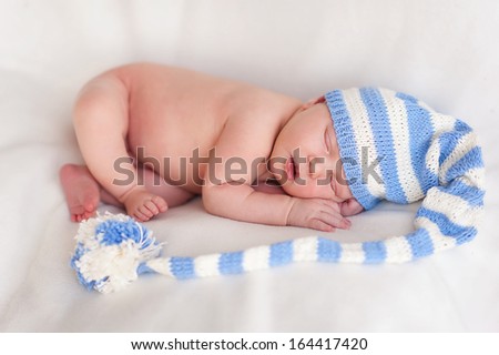 New born baby portrait, lying with hat on head, sleeping