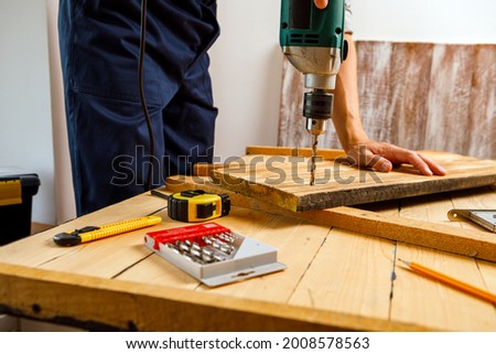 Handyman in blue uniform works with electricity automatic screwdriver. House renovation conception.