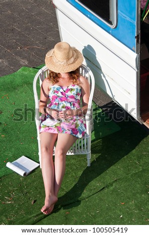 Woman having a nap outside her caravan while on a camping vacation