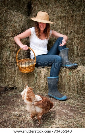 Farm girl in hay barn feeding the chooks and collectiing eggs