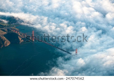 The Golden Gate Bridge rises through dramatic early morning fog seen from above