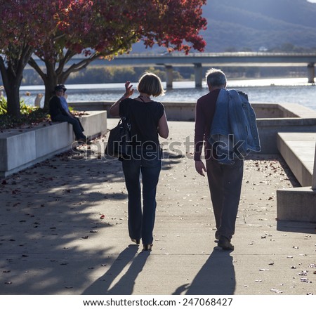 CANBERRA. AUSTRALIA - MAY 05, 2013: Unidentified couple walks along embankment of Burley Griffin Lake. Lake\'s recreational areas are very popular with locals and visitors alike.