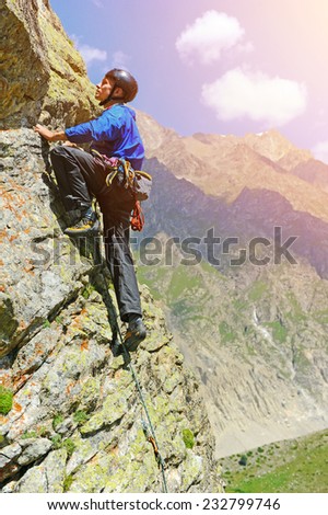 Young man climbs on a rocky wall