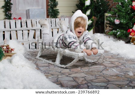 smiling child sledding in yard of winter snow