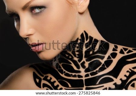 Portrait of attractive young woman with black body art on black background