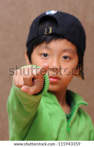 Cute boy with black cap pointing with index finger (focus on finger)