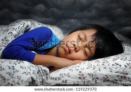 Cute boy having nightmare ( bad dream ) with dark clouds background