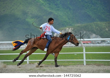 ZHONGDIAN - JUNE 11: participant races during the Shangrila horse racing festival on June 11, 2013 in Zhongdian, China. This festival is the most important horse racing festival in Southwest China.