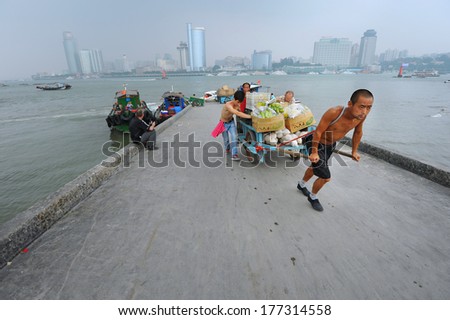 XIAMEN - JULY 7: harbor workers transport goods at Gulangyu harbor on July 7, 2013 in Xiamen, China. Although Xiamen is China\'s no.8 biggest harbor there is still a lot of physical labor activity.