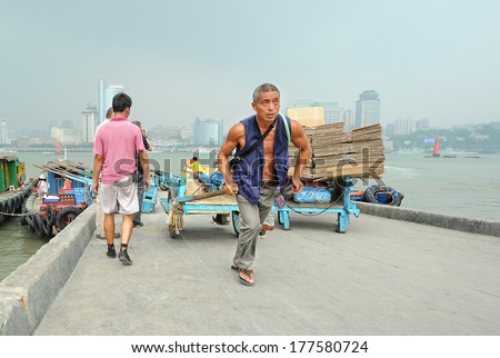 XIAMEN - JULY 7: harbor workers transport goods at Gulangyu harbor on July 7, 2013 in Xiamen, China. Although Xiamen is China\'s no.8 biggest harbor there is still a lot of physical labor activity.