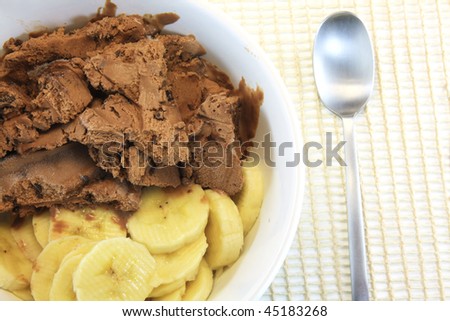 chocolate ice cream and banana on withe plate with silver spoon