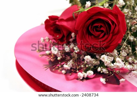 Red roses with baby\'s breath on heart-shaped box of candy