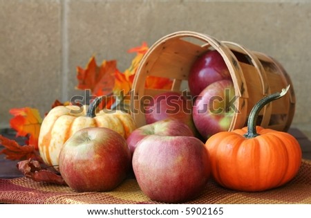Bushel of red apples with pumpkins and autumn leaves
