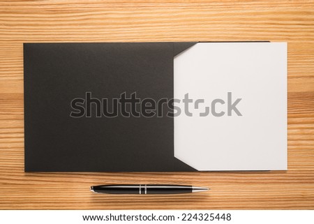 Black envelope with white paper and pen on the table