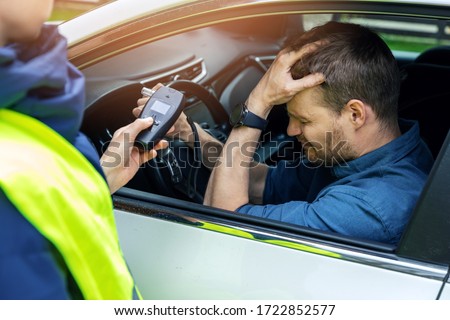 drink and drive concept - sad drunk man sitting in the car after police alcohol test with alcometer Foto d'archivio © 