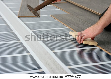 man installing laminate floor over infrared carbon heating system
